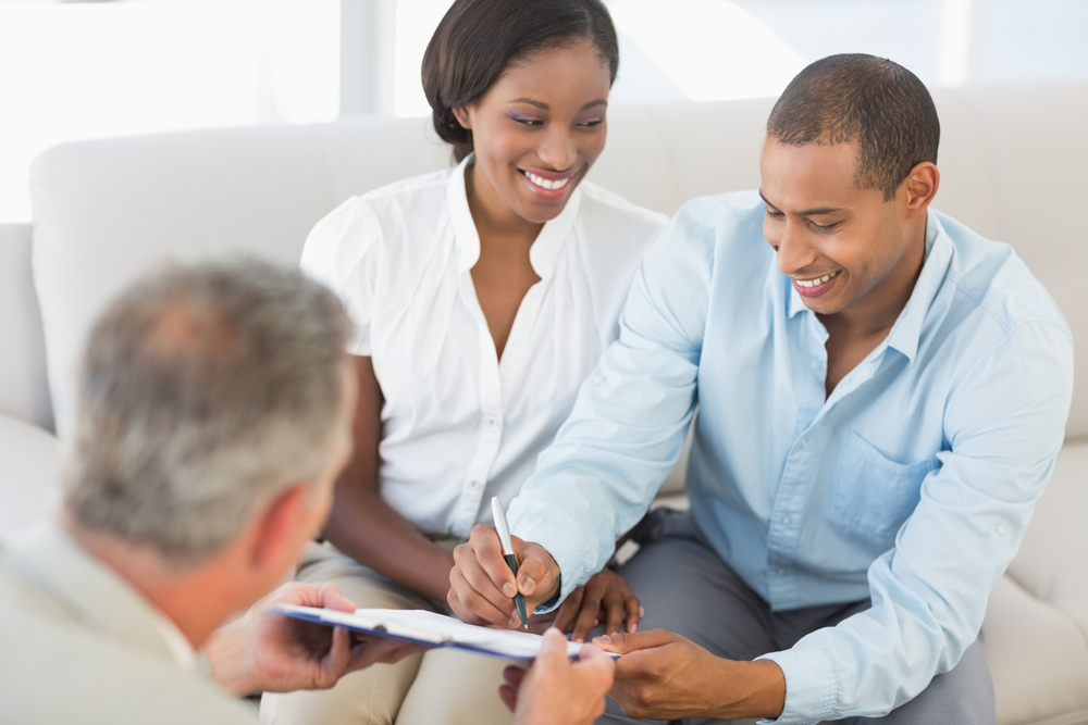 Young smiling couple signing contract on the couch in the office-1
